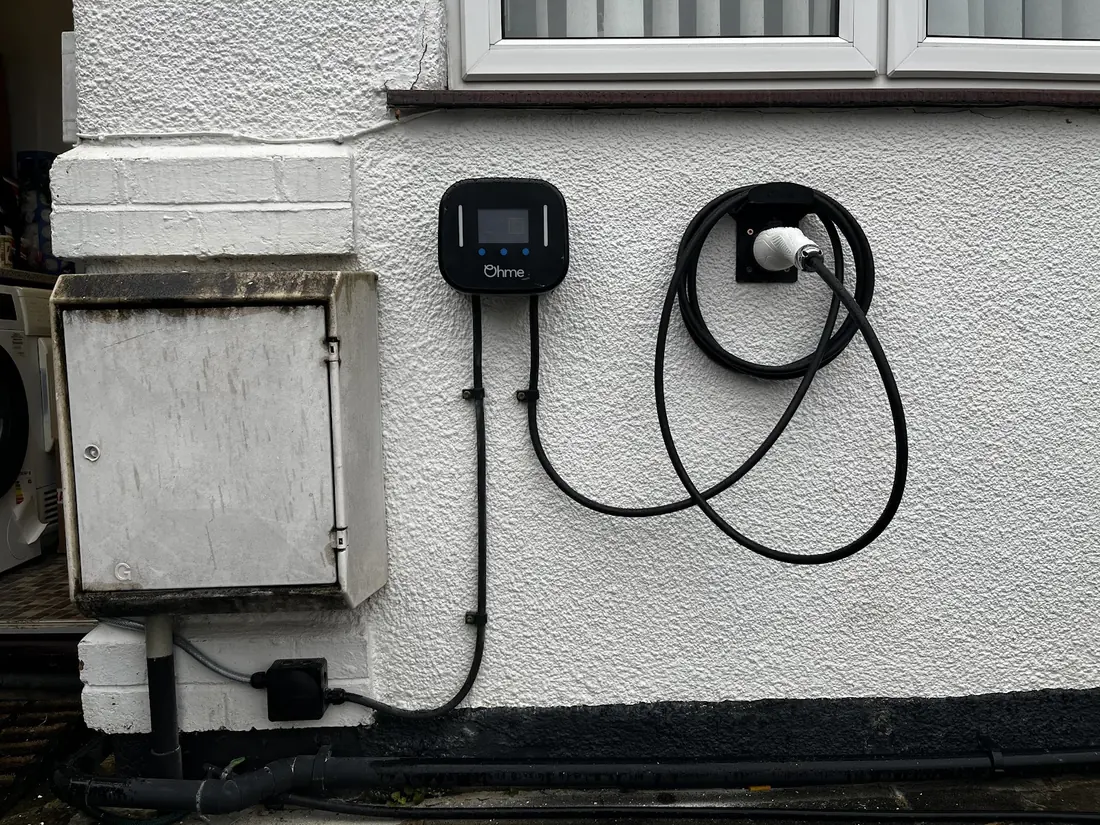 Ohme EV charger installed on an exterior wall with neatly coiled cable