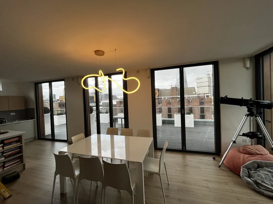 Custom sculptural pendant light fitted in a rooftop apartment dining area with London skyline views